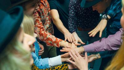 group of students has put them hands on top of each other. they are preparing for cheering.