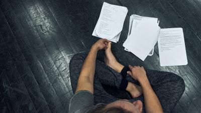 A student is sitting on the floor and reading scripts.