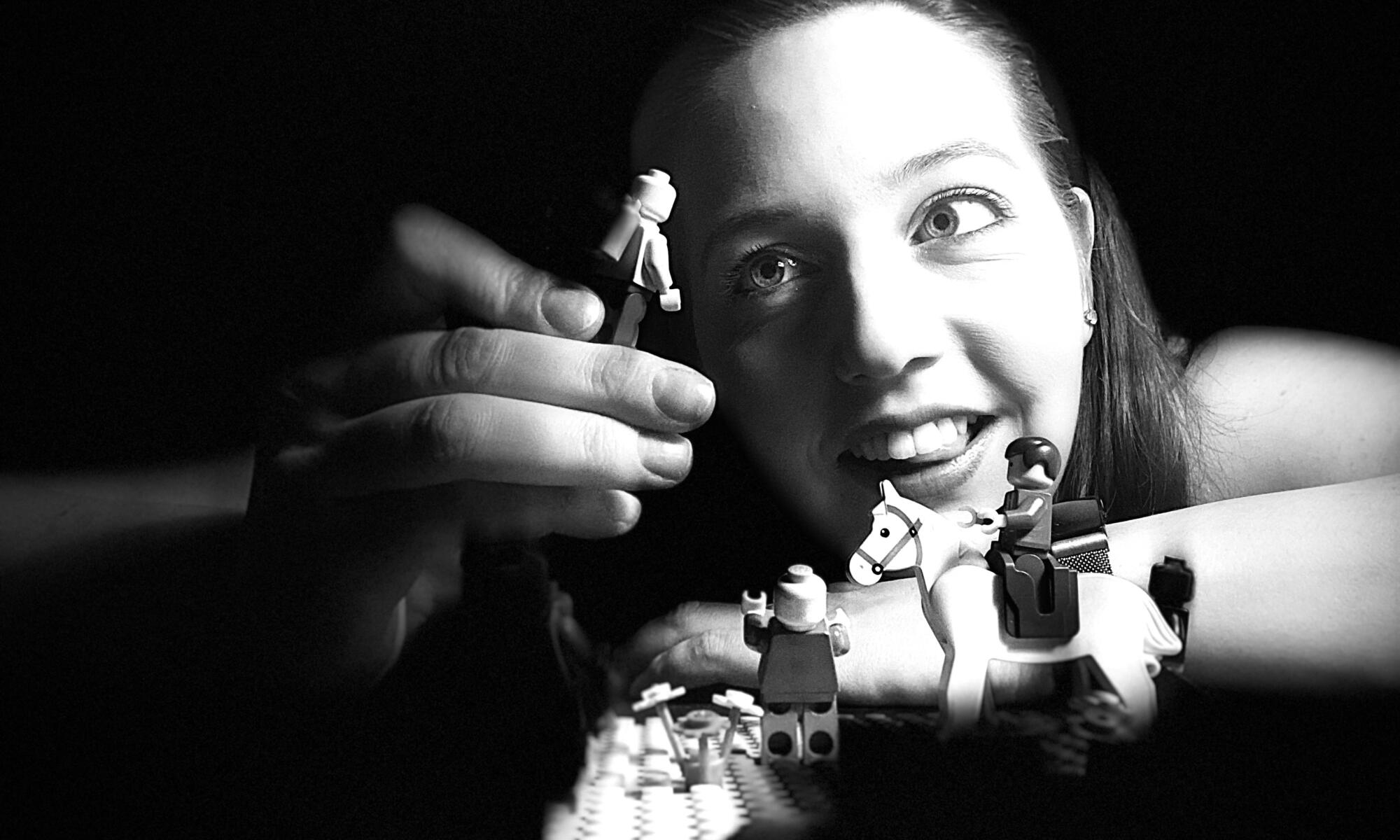Nuori nainen leikkii legofiguureilla mustavalkoisessa kuvassa